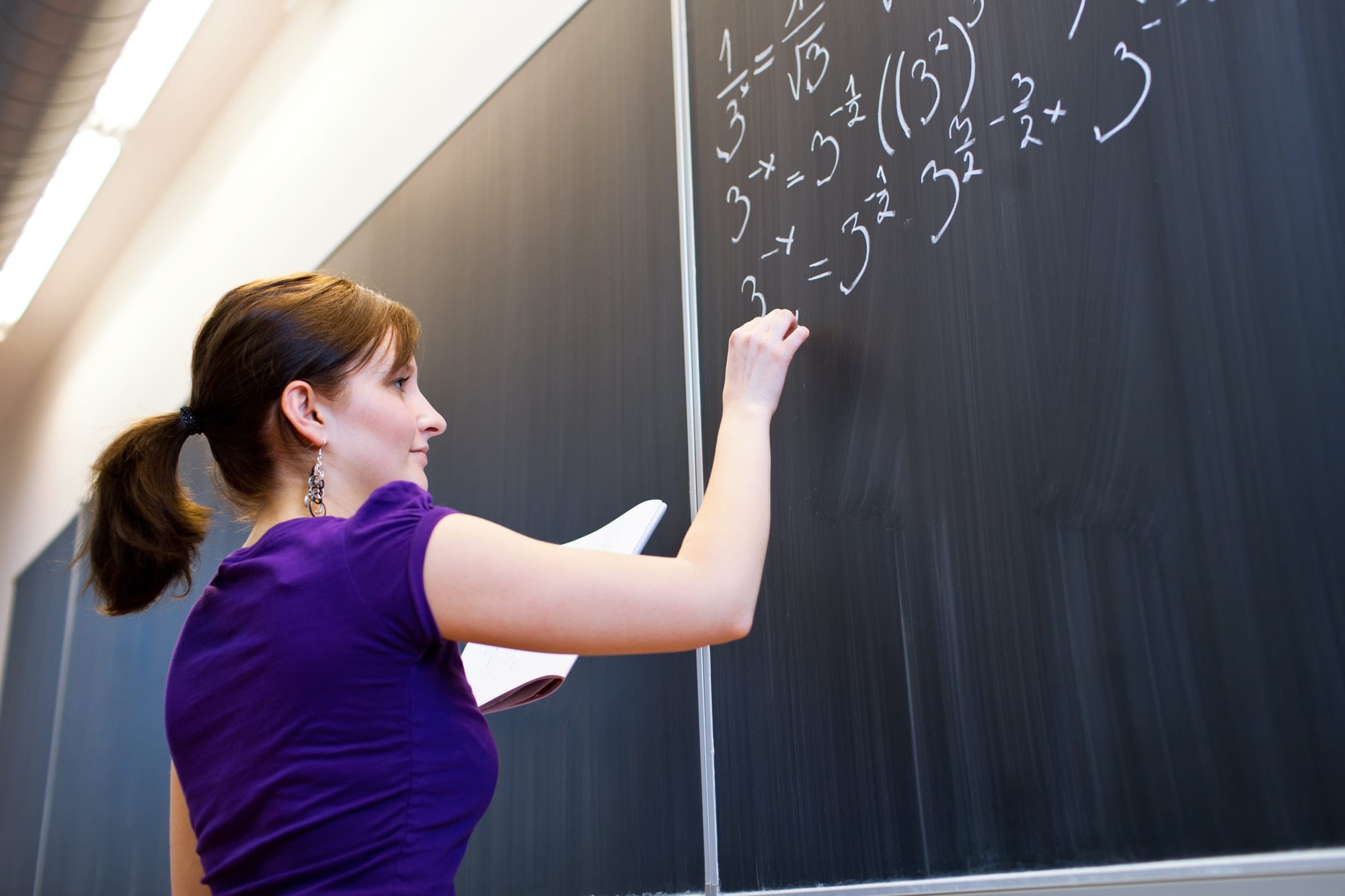 pretty young college student writing on the chalkboard/blackboar